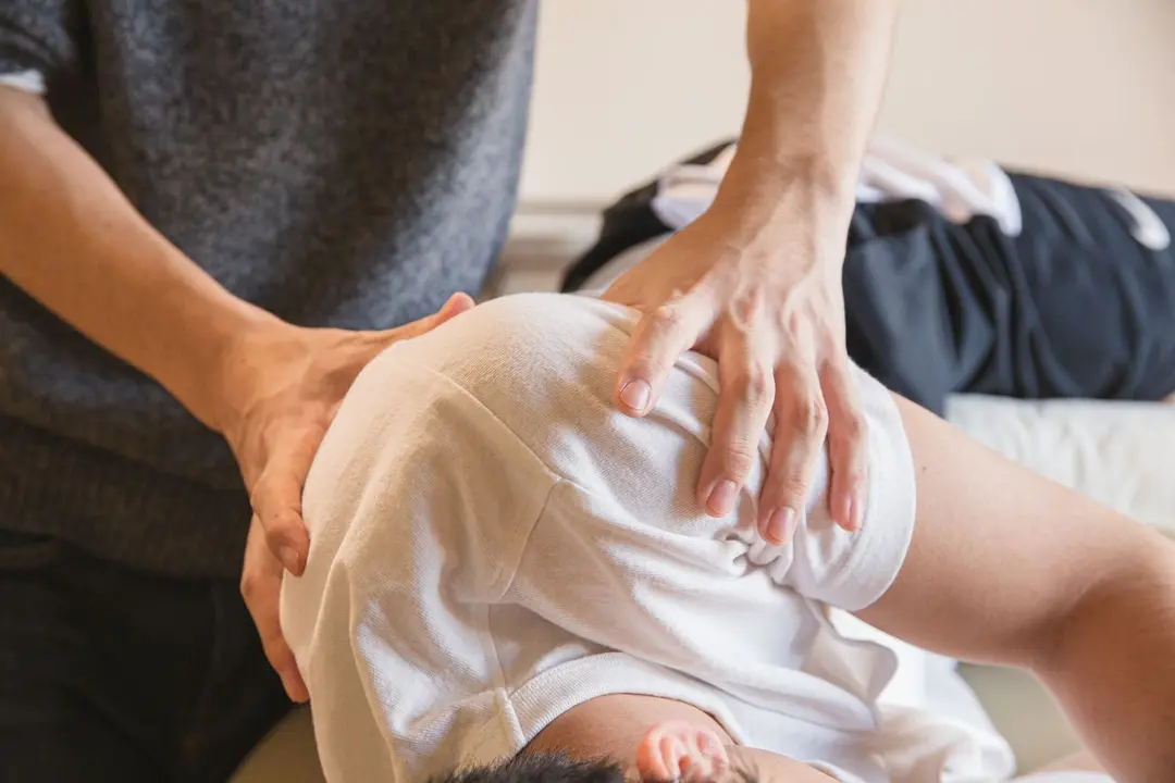 Hands supporting a person’s shoulder during a physical assessment