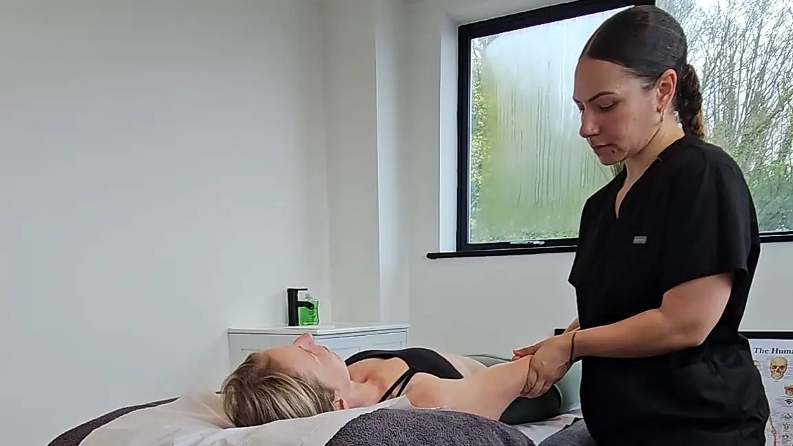Jen assessing shoulder and arm movement with a patient lying on the treatment couch